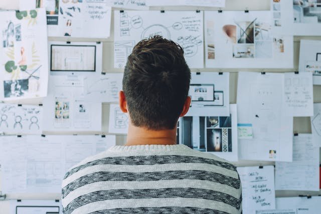 Man looking at a disorganized board of papers.