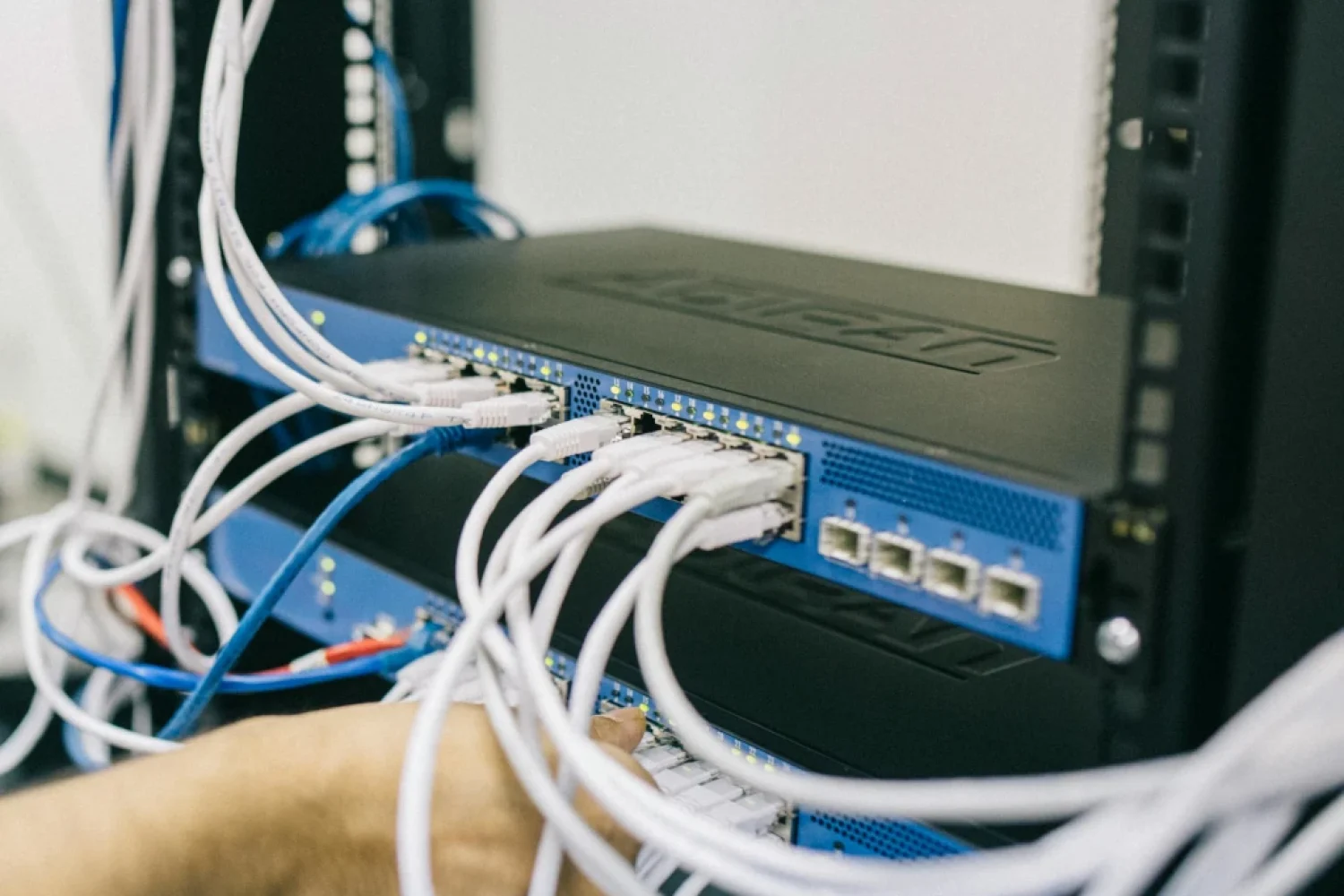 photo of man plugging cable into network equipment